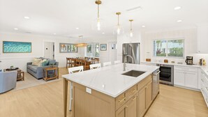A modern kitchen with a central island, stainless steel appliances, and pendant lighting.