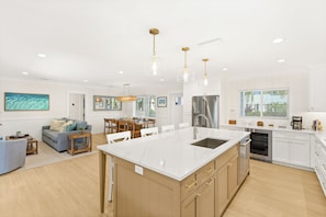 A modern kitchen with a central island, stainless steel appliances, and pendant lighting.