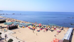 A beach with numerous colorful umbrellas and tents, a sandy beach, and the ocean in the background. - Blue Beach Apartment (Póvoa de Varzim)