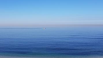Une plage avec une eau d’un bleu limpide et un bateau qui se trouve au loin.