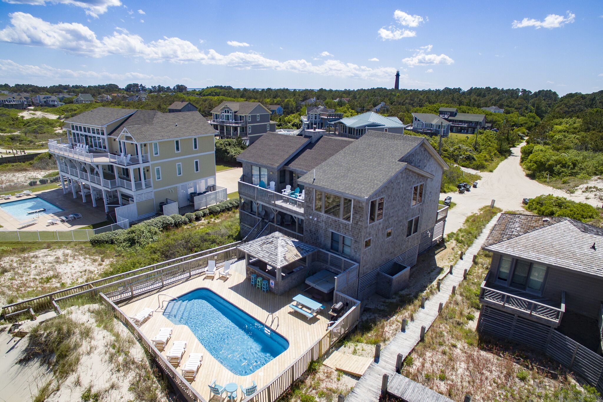 Une propriété située en bord de mer, comprenant plusieurs maisons, une piscine et un chemin d’accès à la plage.