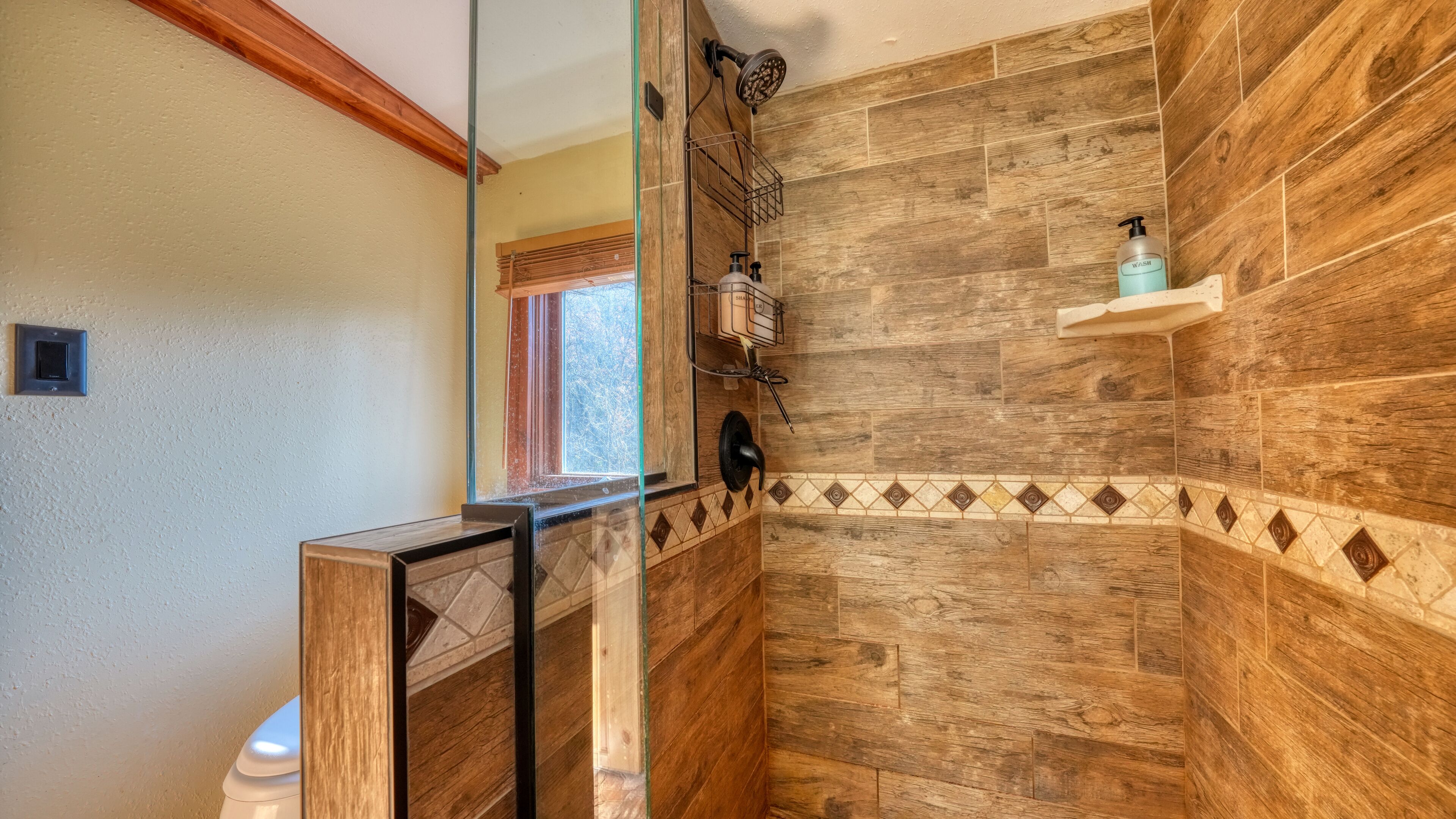 A shower area with wooden paneling and a tiled border.