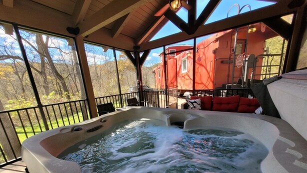 Un jacuzzi en una terraza de madera con vista a un edificio rojo al fondo.
