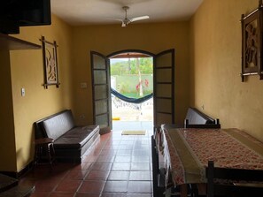 A room with two beds, a ceiling fan, and a view of a garden through open doors. - Residencial Rosi (Caraguatatuba)