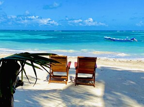 Two wooden beach chairs facing the ocean with a boat in the distance. - Little Corn Beach and Bungalow (Corn Islands)