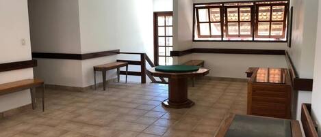 A spacious room with a billiards table, a small seating area, and a window with a view.