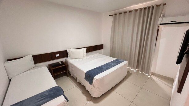 A hotel room with two beds, a nightstand, a wardrobe, and a curtain. - Rede Andrade Estrela Dalva Praia Hotel (Porto Seguro)