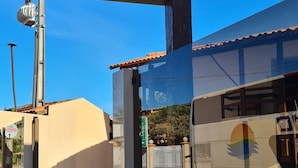 A sign for Hotel Monte Pascoal with a logo, a clear blue sky, and a building with a tiled roof in the background. - Rede Andrade Estrela Dalva Praia Hotel (Porto Seguro)