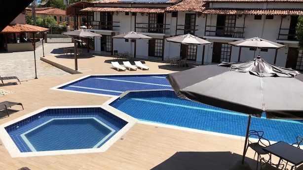 A pool area with multiple swimming pools, lounge chairs, and umbrellas. - Rede Andrade Estrela Dalva Praia Hotel (Porto Seguro)