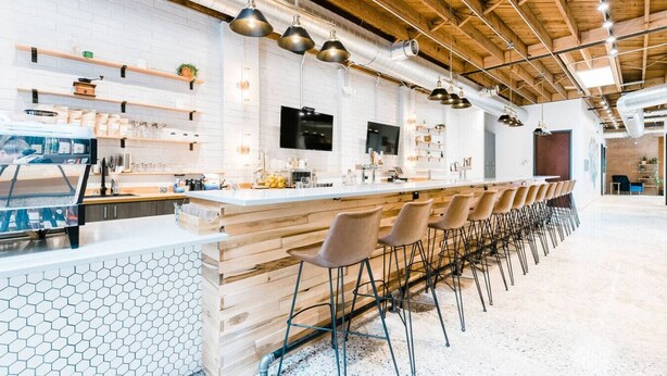 Una cucina moderna con un'ampia zona bancone, sgabelli in legno e un rivestimento a mosaico esagonale.