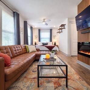 Un salon moderne avec un canapé en cuir, une table basse en verre et une cheminée.
