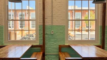 A room with two wooden benches, large windows, and hanging pendant lights.