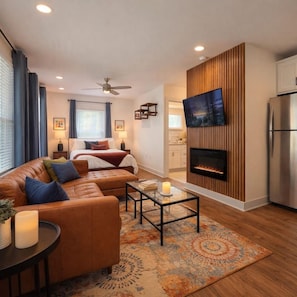 A modern living room with a sofa, coffee table, and a fireplace. - Tiny Home Retreat • Greenway • NoDa & Uptown (Charlotte)