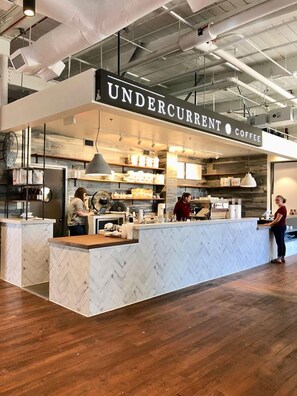 A coffee shop interior with a marble counter, industrial ceiling, and visible coffee-making equipment. - Tiny Home Retreat • Greenway • NoDa & Uptown (Charlotte)