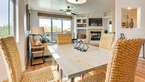 A modern living room with a wooden dining table, woven chairs, and a ceiling fan.