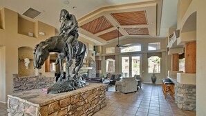 A spacious lobby with a stone fireplace, a large sculpture of a horse and rider, and a seating area with a stone accent wall.