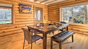 Ein Holzblockhaus-Interieur mit einem Esstisch, der für vier Personen gedeckt ist, einer Bank und einem an der Wand befestigten Schild.