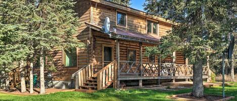 A log cabin with a porch, stairs, and a satellite dish.