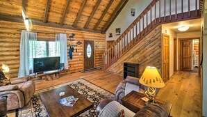 Ein rustikales Holzhaus-Interieur mit einer Holztreppe, einem Fernseher und einem Kamin.