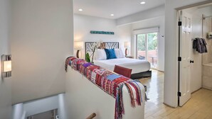 Quarto moderno com uma cama grande, manta colorida e vista para o exterior.
