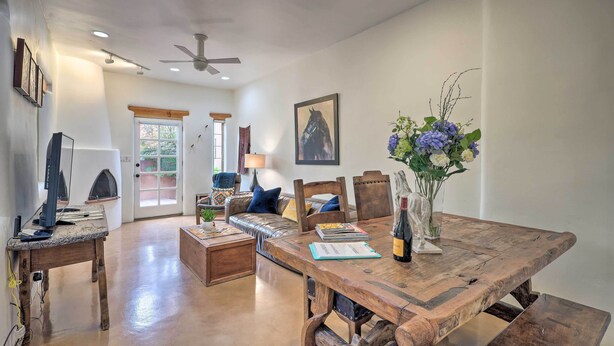 Uma sala de estar espaçosa com uma mesa de jantar de madeira, um sofá e um ventilador de teto.