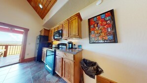 Une cuisine avec des meubles en bois, un four à micro-ondes et une machine à café. Une porte donne accès à un balcon avec vue.