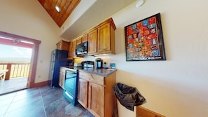 A kitchen with wooden cabinets, a microwave, and a coffee maker. There is a door leading to a balcony with a view.