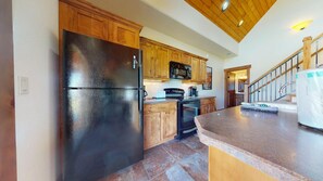 A kitchen with wooden cabinets, a black refrigerator, a stove, and a countertop.