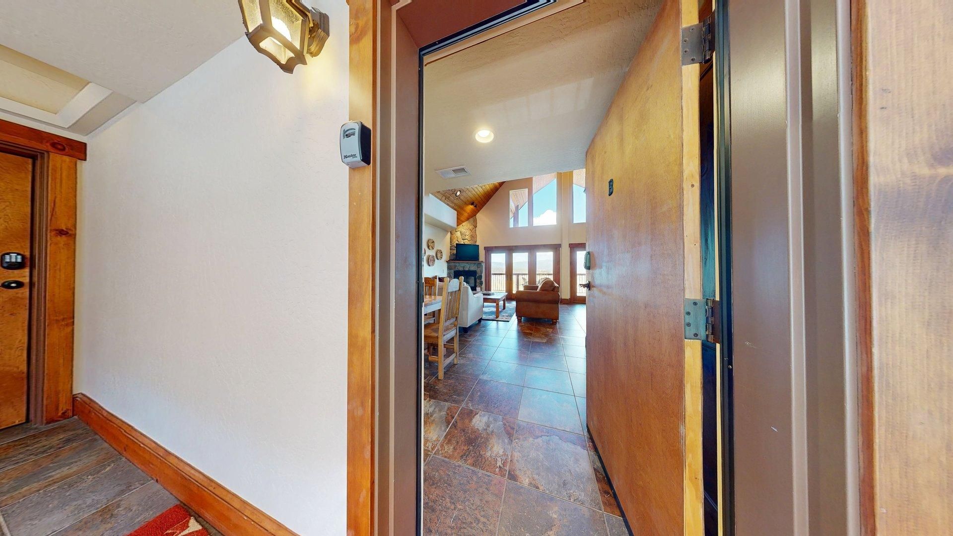 A hallway leading to a living area with a fireplace, wooden flooring, and a view of the outdoors.