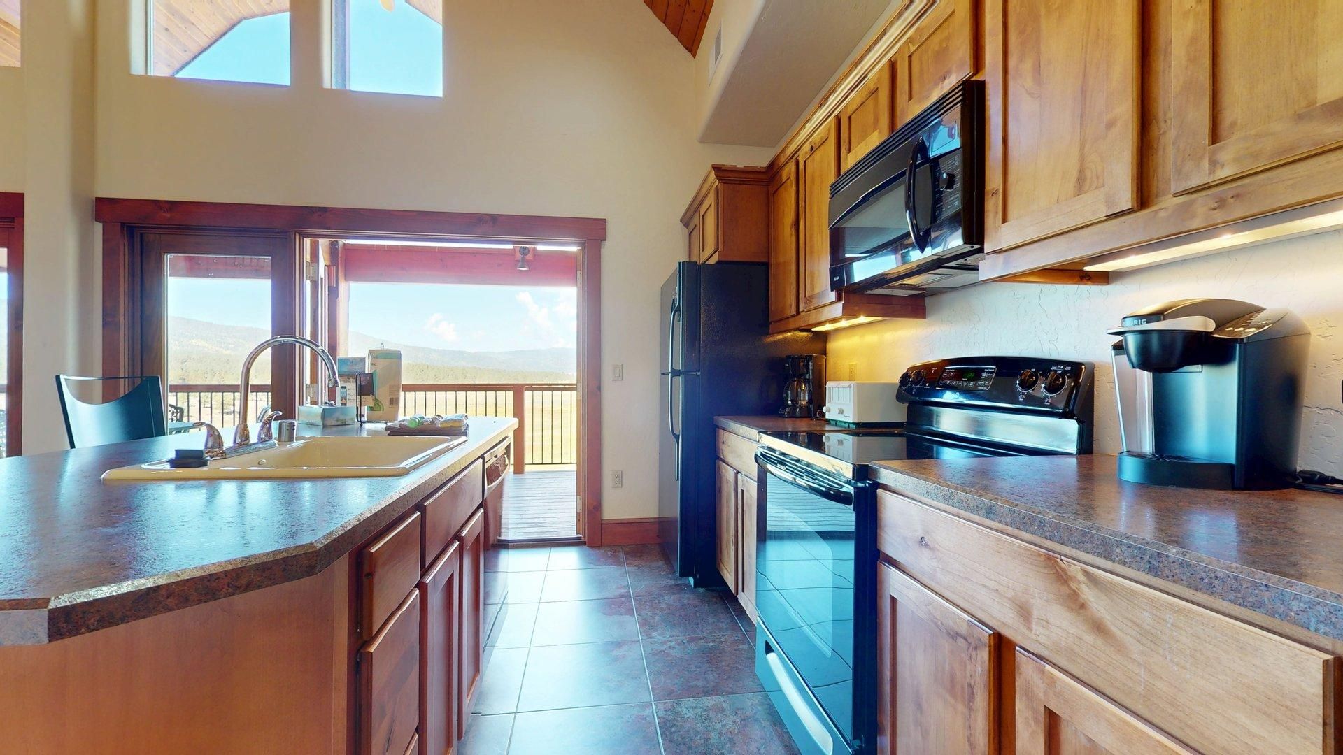 Una cocina con armarios de madera, un refrigerador de acero inoxidable, un microondas, una estufa y una cafetera.