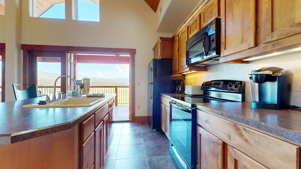 A kitchen with wooden cabinets, a stainless steel refrigerator, a microwave, a stove, and a coffee maker.