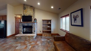Cozy living room with a fireplace, flat-screen TV, and shelving unit.