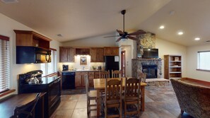 Enjoy meals and gatherings in this well-appointed kitchen and dining area with a stone fireplace and comfortable seating.