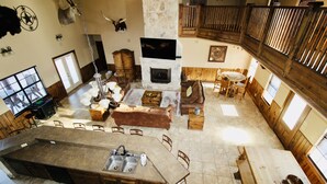 A spacious living area with a stone fireplace, wooden furniture, and a large island with a sink.