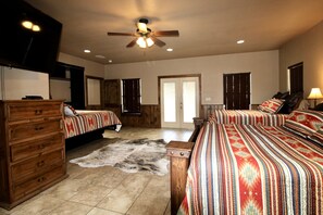 A bedroom with two beds, a wooden dresser, a ceiling fan, and a large rug. - Beautiful 5/5.5 home on 5 acres w/private pool. River access 2 m. away (Rio Frio)