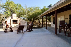 An outdoor patio with stone-built barbecue area, wooden chairs, and a covered seating area. - Beautiful 5/5.5 home on 5 acres w/private pool. River access 2 m. away (Rio Frio)