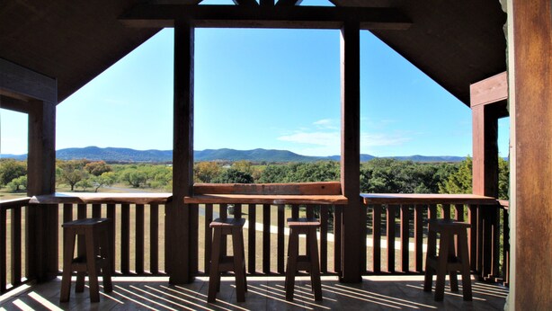 A wooden deck with a view of mountains and trees.
