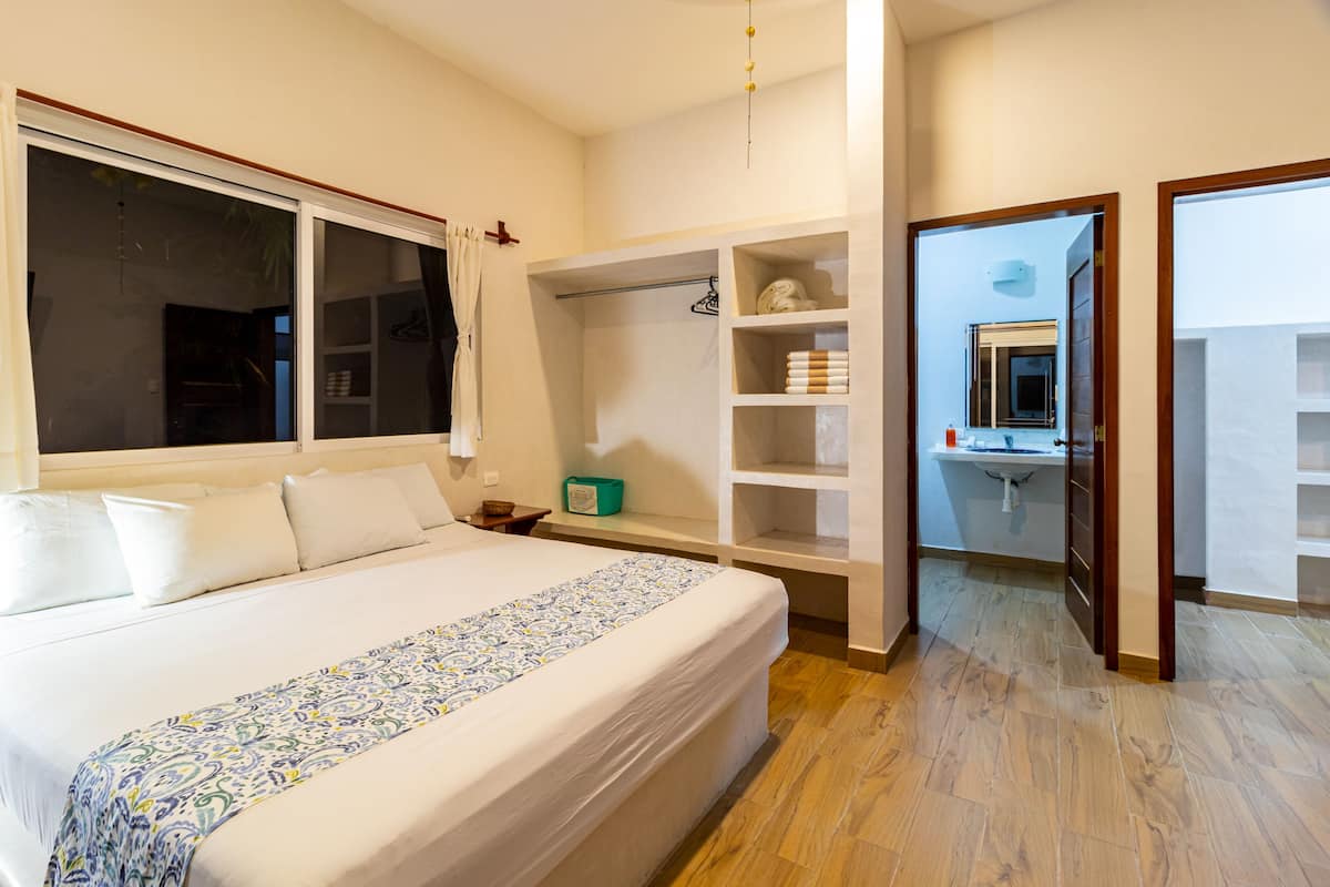 Un dormitorio con una cama grande, estanterías empotradas, un vestidor y un baño visible a través de una puerta abierta.