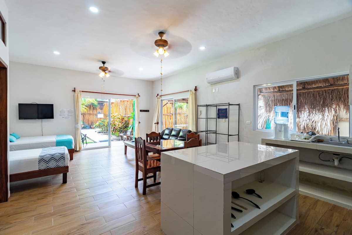 Una cocina moderna con una isla central, suelo de madera y un comedor con mesa y sillas.