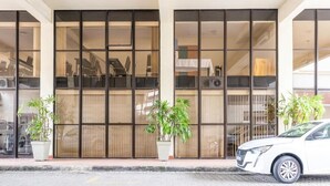 A building with large glass windows, potted plants, and a parked car. - Dexter Hotel (Volta Redonda)