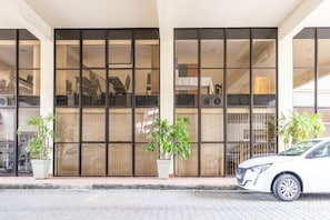 A building with large glass windows, potted plants, and a parked car. - Dexter Hotel (Volta Redonda)
