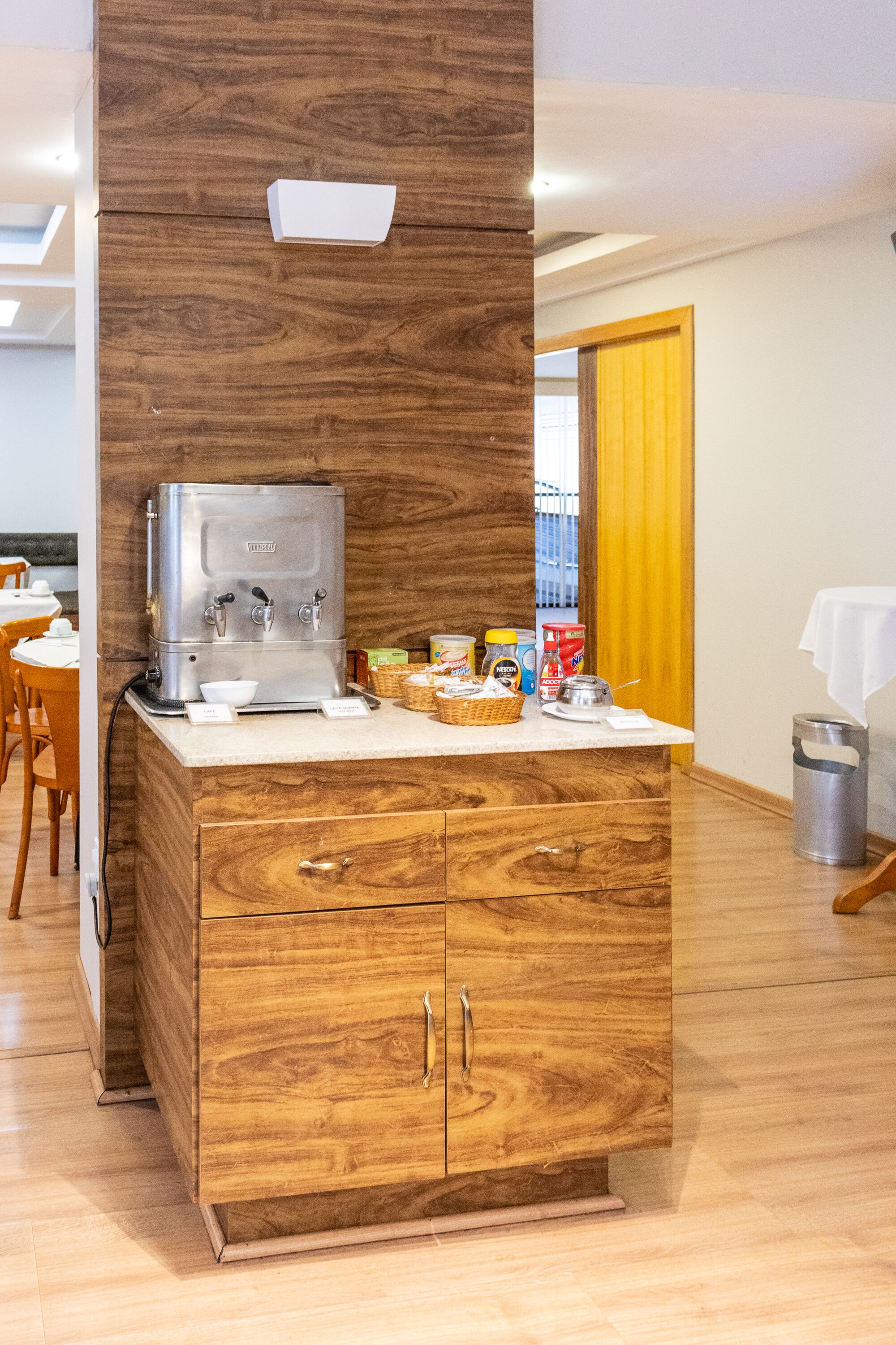 Una kitchenette con cafetera, muebles de madera y una pequeña encimera con diversos objetos.