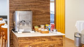 Una kitchenette con cafetera, muebles de madera y una pequeña encimera con diversos objetos.