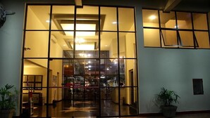 A hotel entrance with a glass door, a reception desk inside, and potted plants outside. - Dexter Hotel (Volta Redonda)