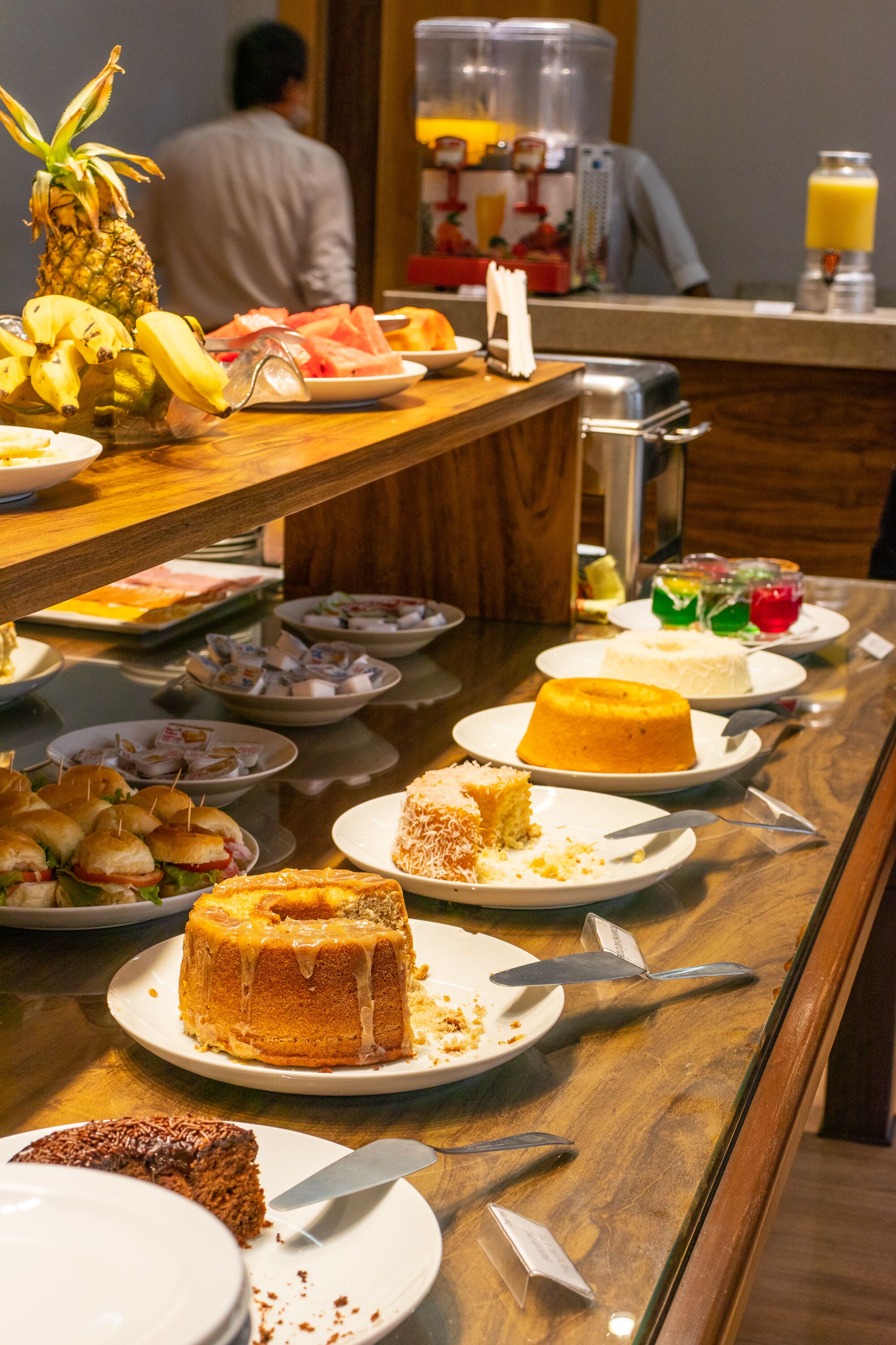 A buffet table with various dishes including cakes, sandwiches, and fruits.