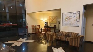 A lobby with a star-patterned floor, a seating area with striped chairs, a map on the wall, and a parking area with a car. - Dexter Hotel (Volta Redonda)