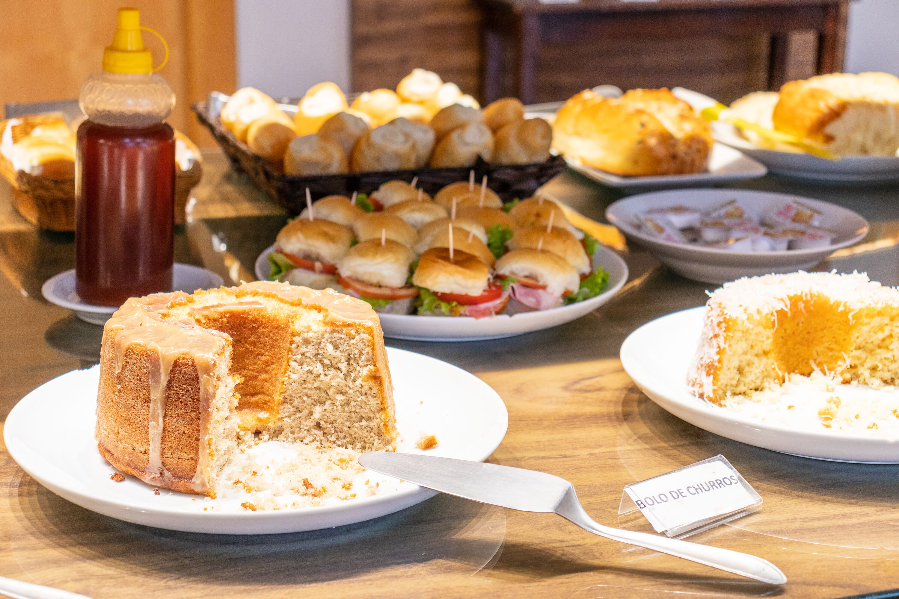 A buffet table with various food items including a cake, sandwiches, and a bowl of rice.