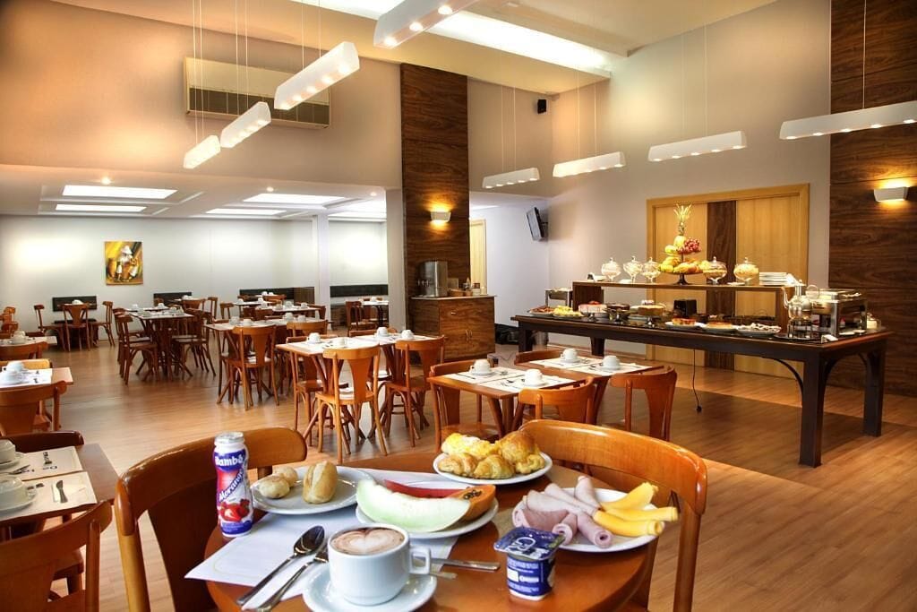 A hotel dining area with multiple tables, chairs, and a buffet setup.