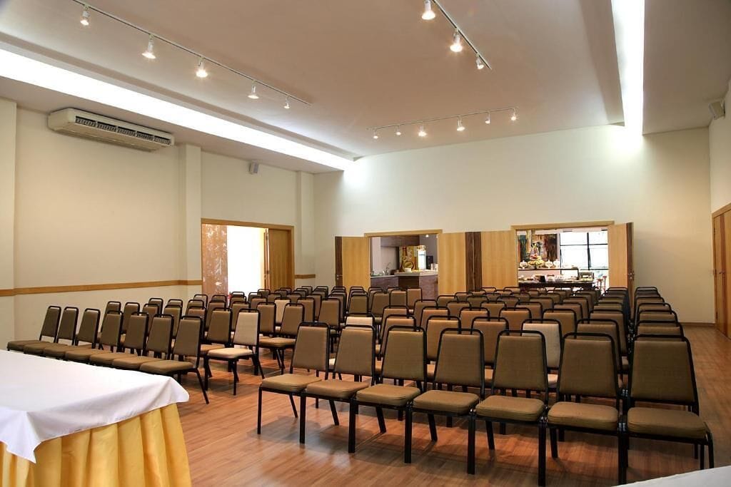A conference room with rows of chairs, a table, and a kitchenette area.