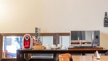 A breakfast area with a coffee maker, microwave, and dining table with chairs.